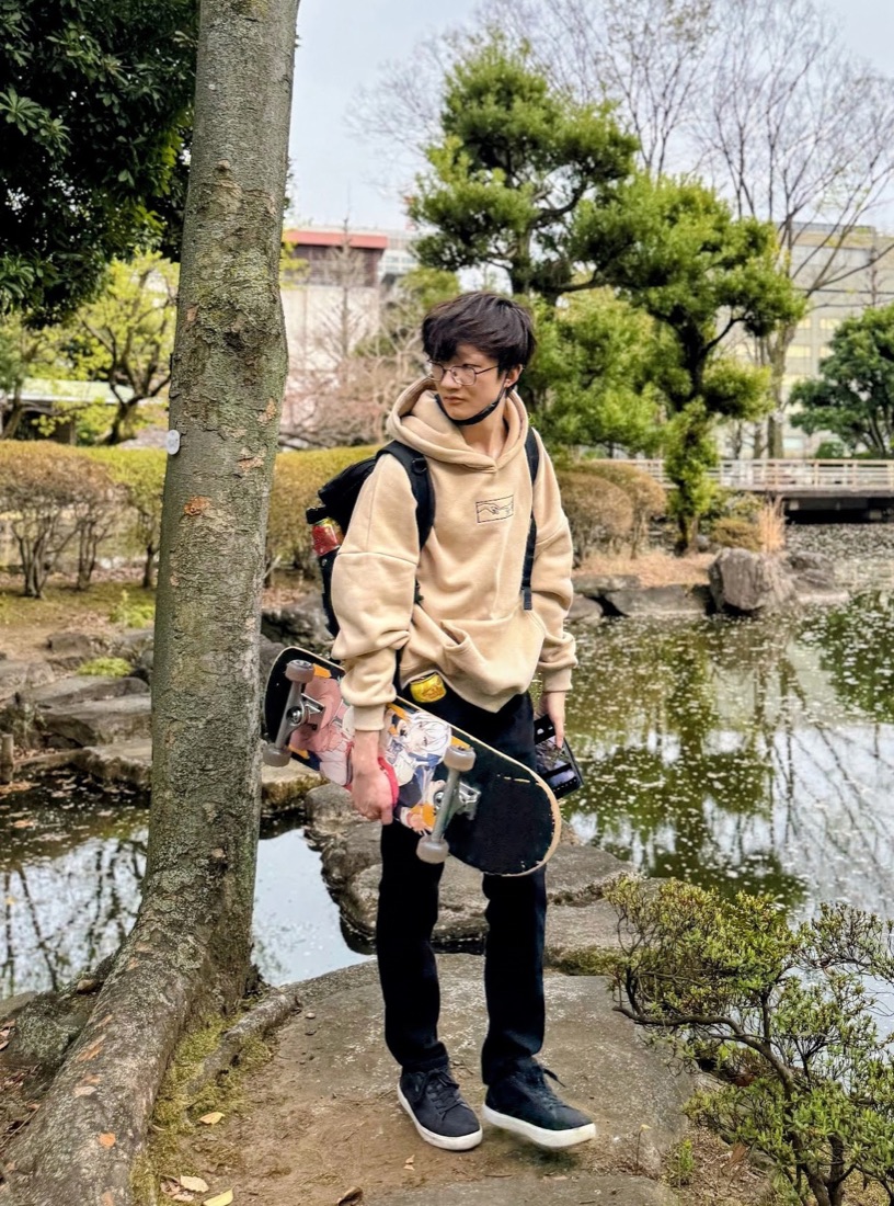 Justin holding a skateboard by a pond